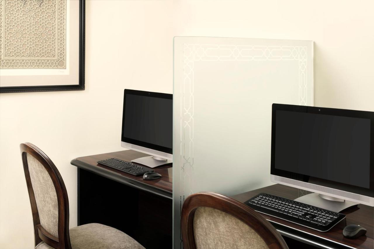 Intercontinental Dar Al Iman Madinah By Ihg Hotel Medina Ngoại thất bức ảnh The photo shows a workspace featuring two computers set up on a dark wooden desk. Each computer has a monitor and a keyboard. A frosted glass partition is placed between the two workstations, providing some privacy. In the background, there is a fram
