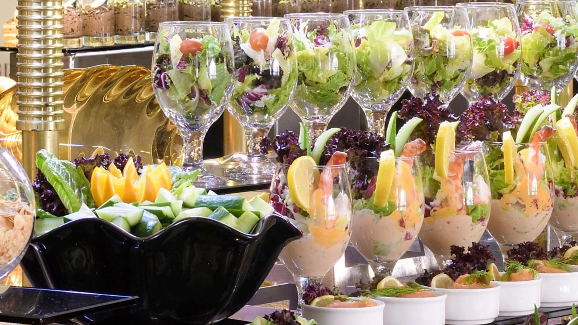 Intercontinental Dar Al Iman Madinah By Ihg Hotel Medina Ngoại thất bức ảnh The photo features an elegant display of food items. In the background, there are several clear glasses filled with vibrant salads, featuring various types of greens and garnishes. In the foreground, there is a decorative black bowl containing cut pi