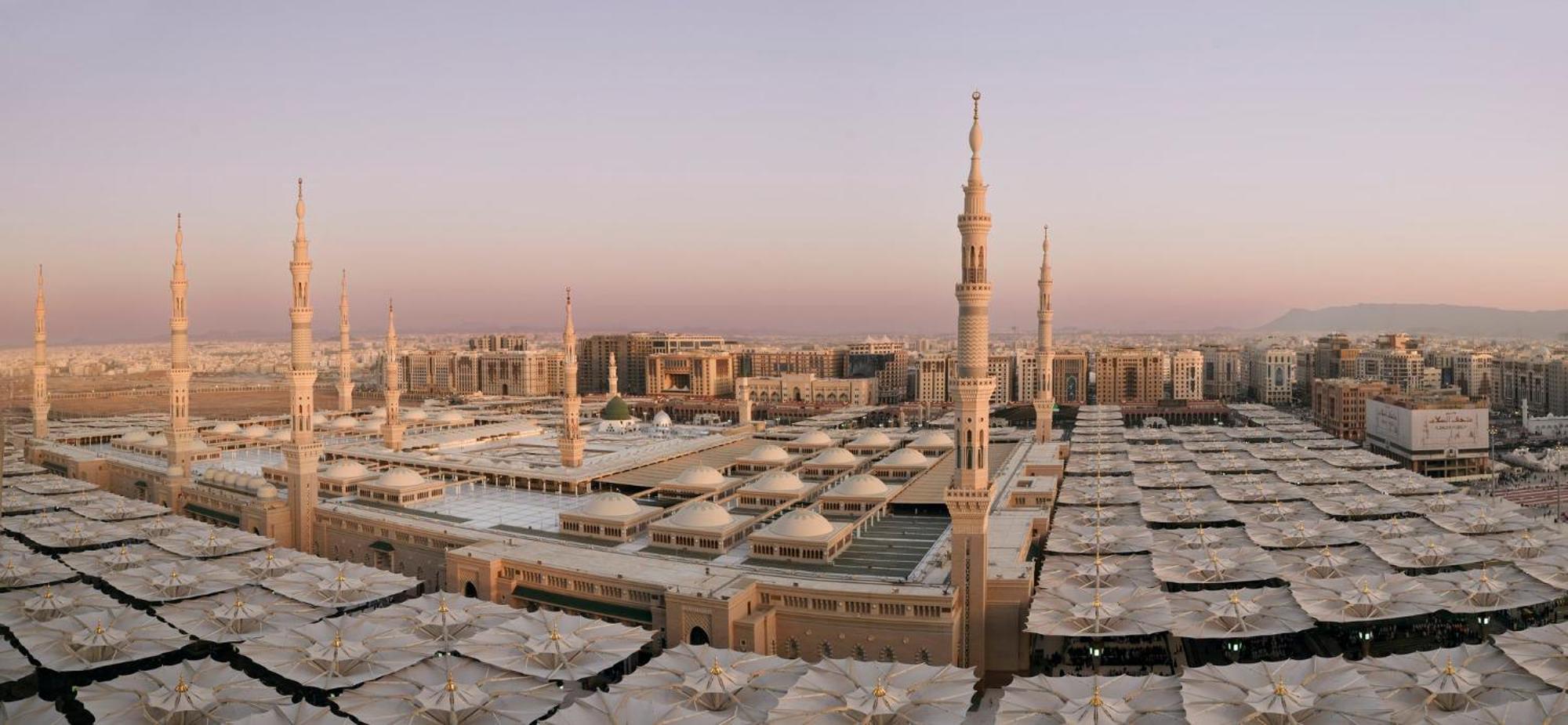 Intercontinental Dar Al Iman Madinah By Ihg Hotel Medina Ngoại thất bức ảnh The photo shows an aerial view of the Al-Masjid an-Nabawi, or the Prophet's Mosque, located in Medina, Saudi Arabia. The mosque features distinct minarets, large white domes, and expansive open areas with large umbrellas that provide shade for visito