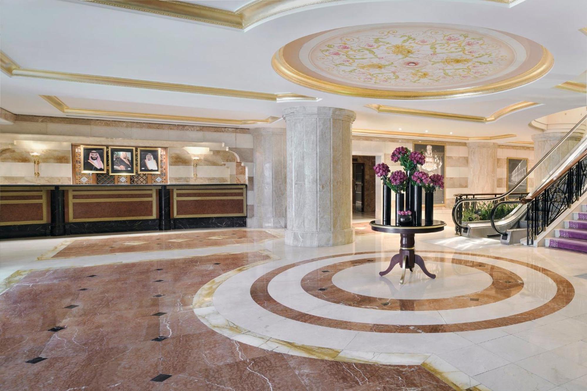 Intercontinental Dar Al Iman Madinah By Ihg Hotel Medina Ngoại thất bức ảnh The photo shows a luxurious hotel lobby. The space features elegant marble flooring with circular designs, complemented by a large, decorative ceiling. In the center, there is a round table adorned with a floral arrangement. Behind the table, a recep