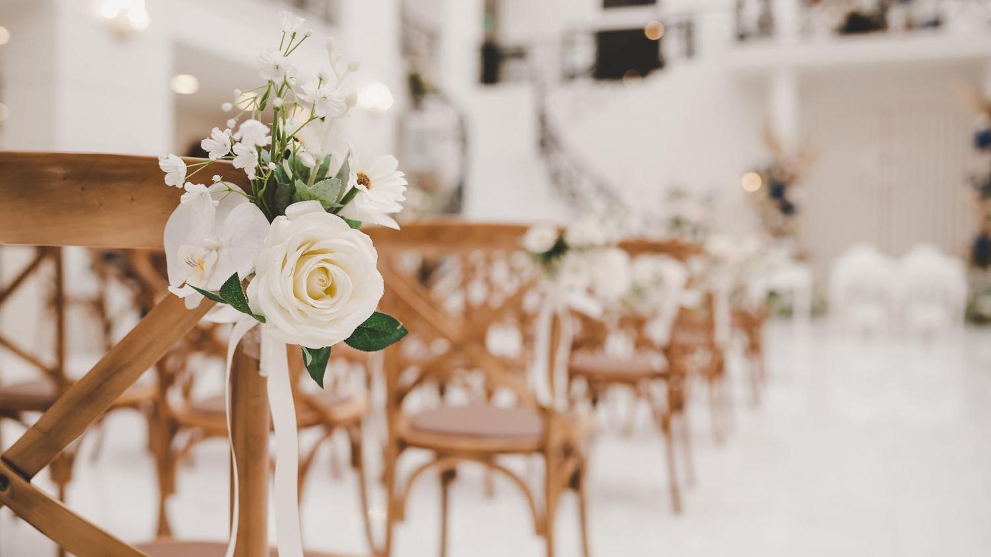 Intercontinental Dar Al Iman Madinah By Ihg Hotel Medina Ngoại thất bức ảnh The photo showcases a beautifully arranged event space, likely set up for a wedding or special occasion. In the foreground, wooden chairs are neatly lined up, some adorned with decorative floral arrangements. The flowers include white roses and small