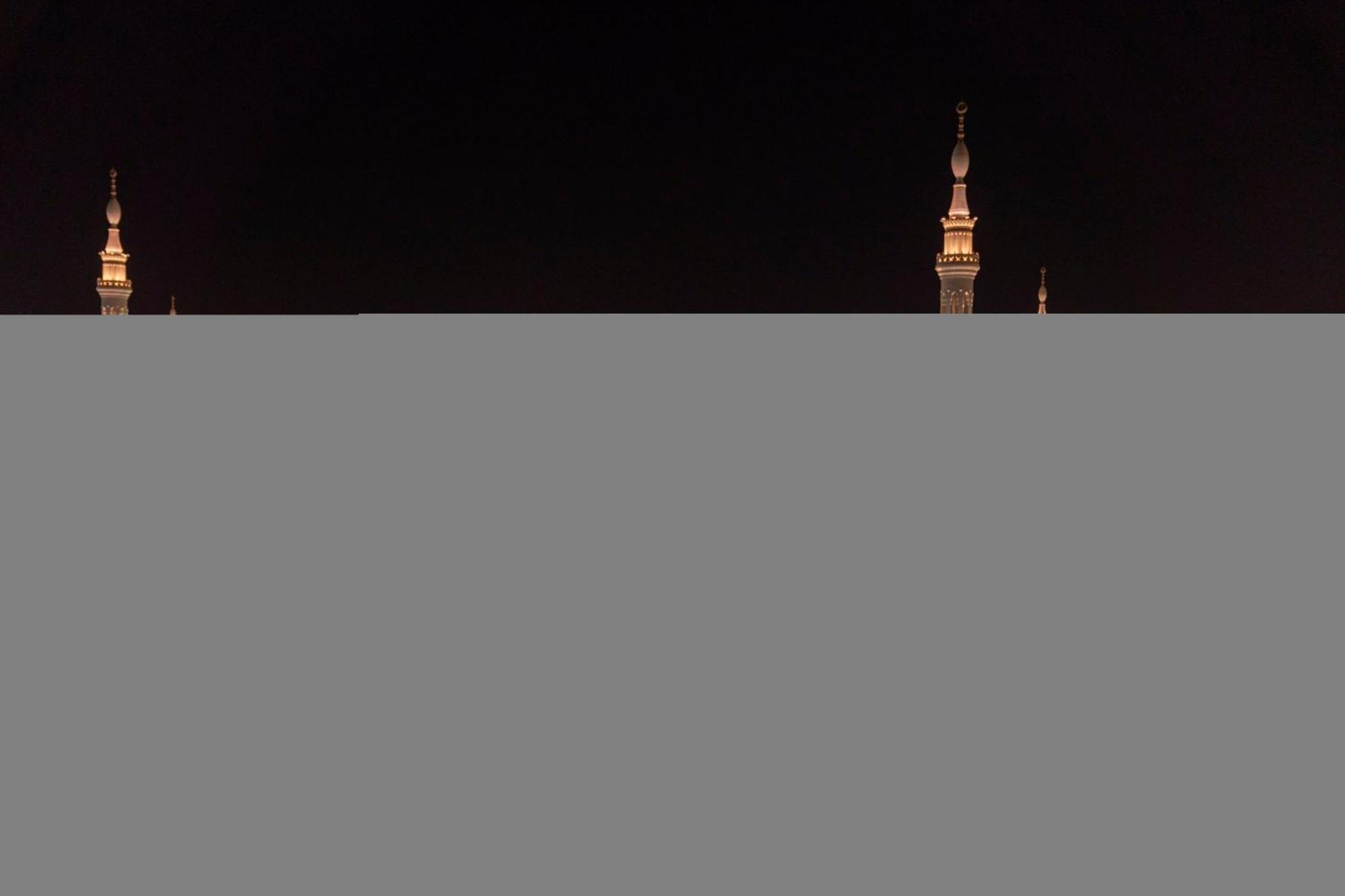 Intercontinental Dar Al Iman Madinah By Ihg Hotel Medina Ngoại thất bức ảnh The image appears to show a night scene featuring tall structures with pointed tops, likely minarets, illuminated against a dark background. The lighting creates a striking contrast, highlighting the architectural details of the structures. The overa