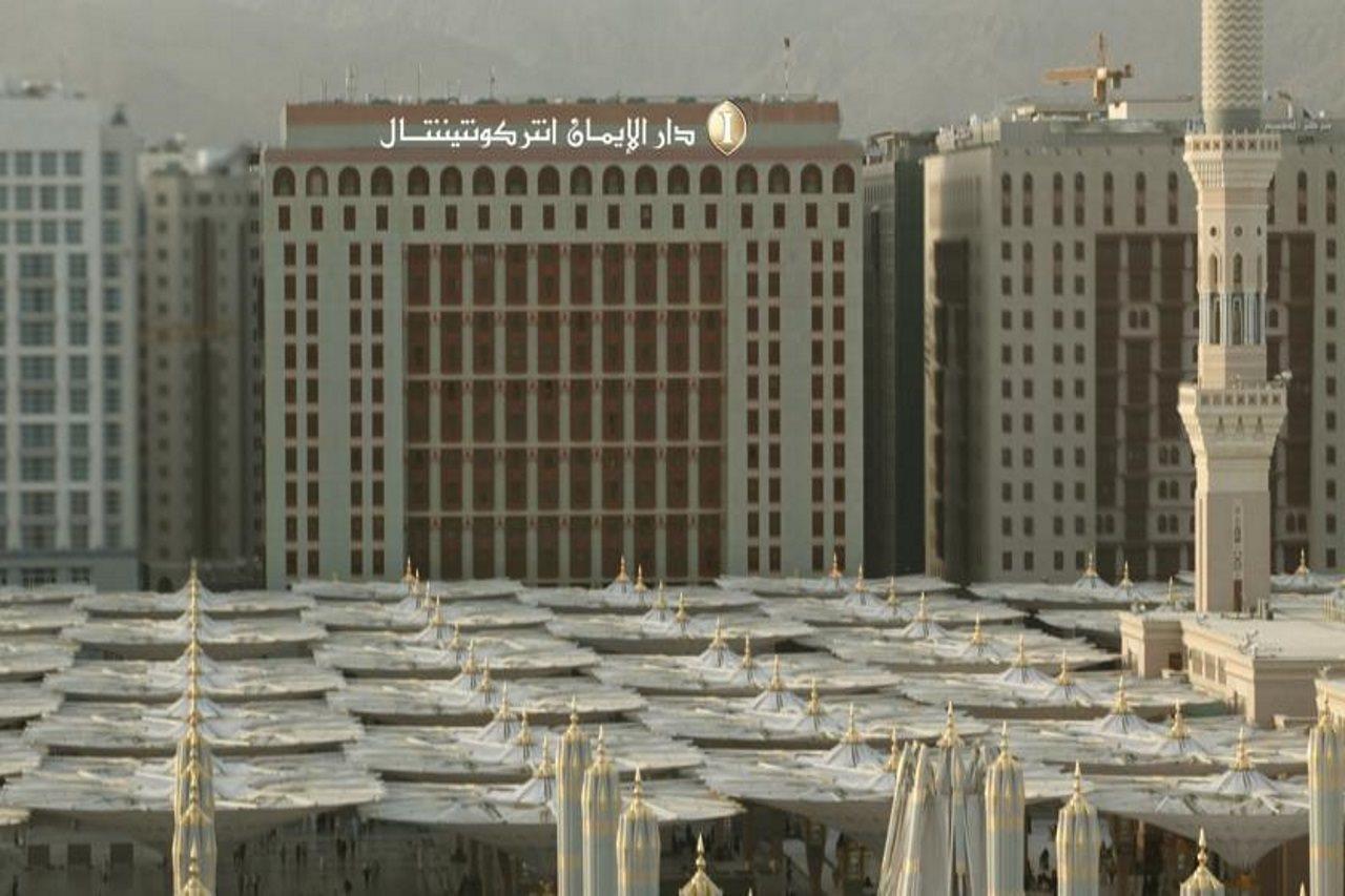 Intercontinental Dar Al Iman Madinah By Ihg Hotel Medina Ngoại thất bức ảnh The photo shows a view of a large building with a modern architectural design, which appears to be a hotel or a commercial establishment. In front of the building, there are several large white canopies that provide shade, likely in a public space or