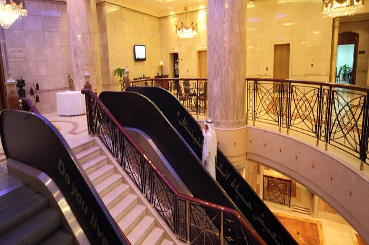 Intercontinental Dar Al Iman Madinah By Ihg Hotel Medina Nội địa bức ảnh The photo depicts an elegant interior space, likely within a hotel or a large building. There is a grand staircase visible, which features a combination of stairs and escalators. The design includes decorative railings and marble pillars, contributin
